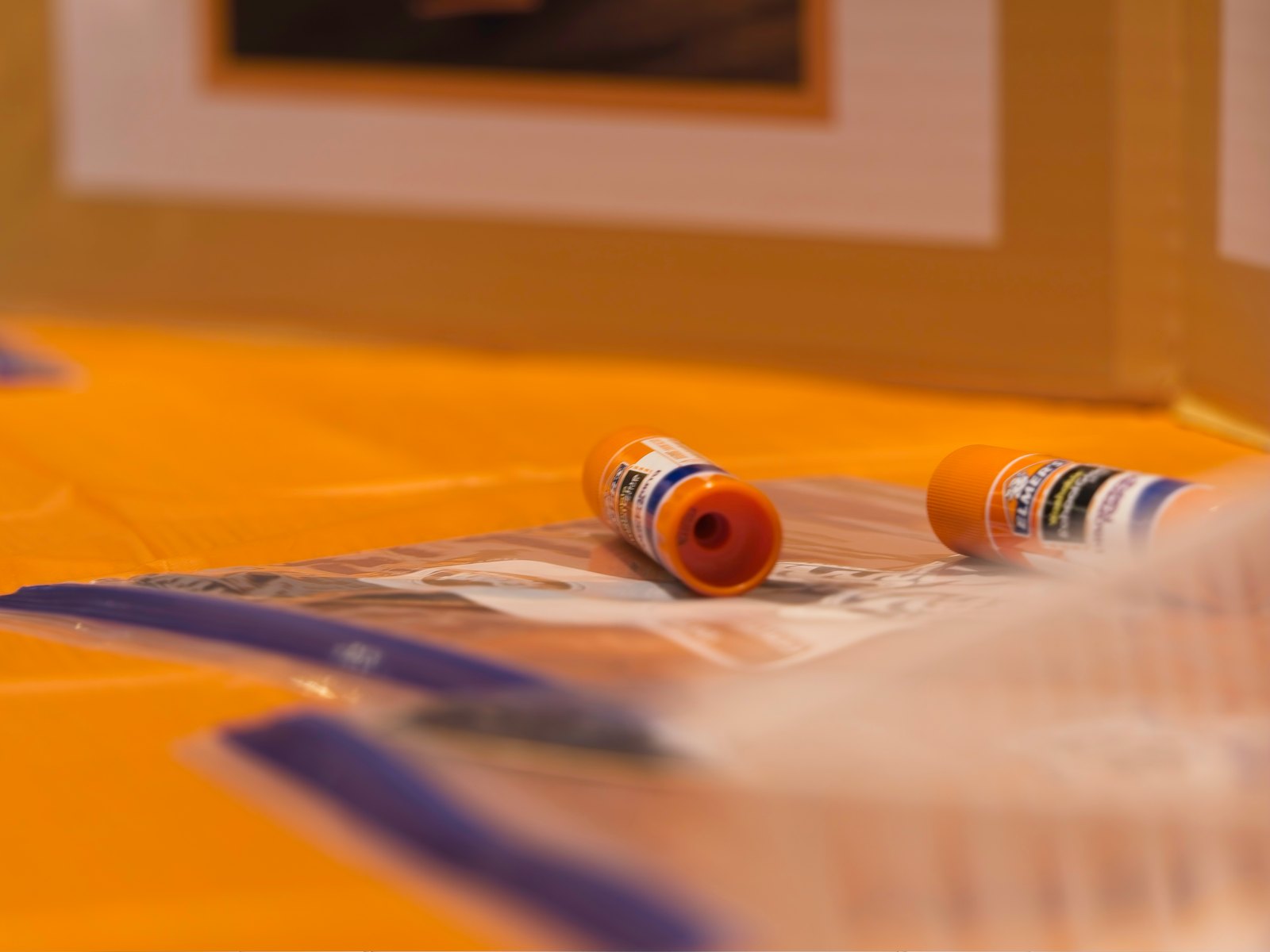 Close-up detail of glue sticks on a yellow craft table at the festival