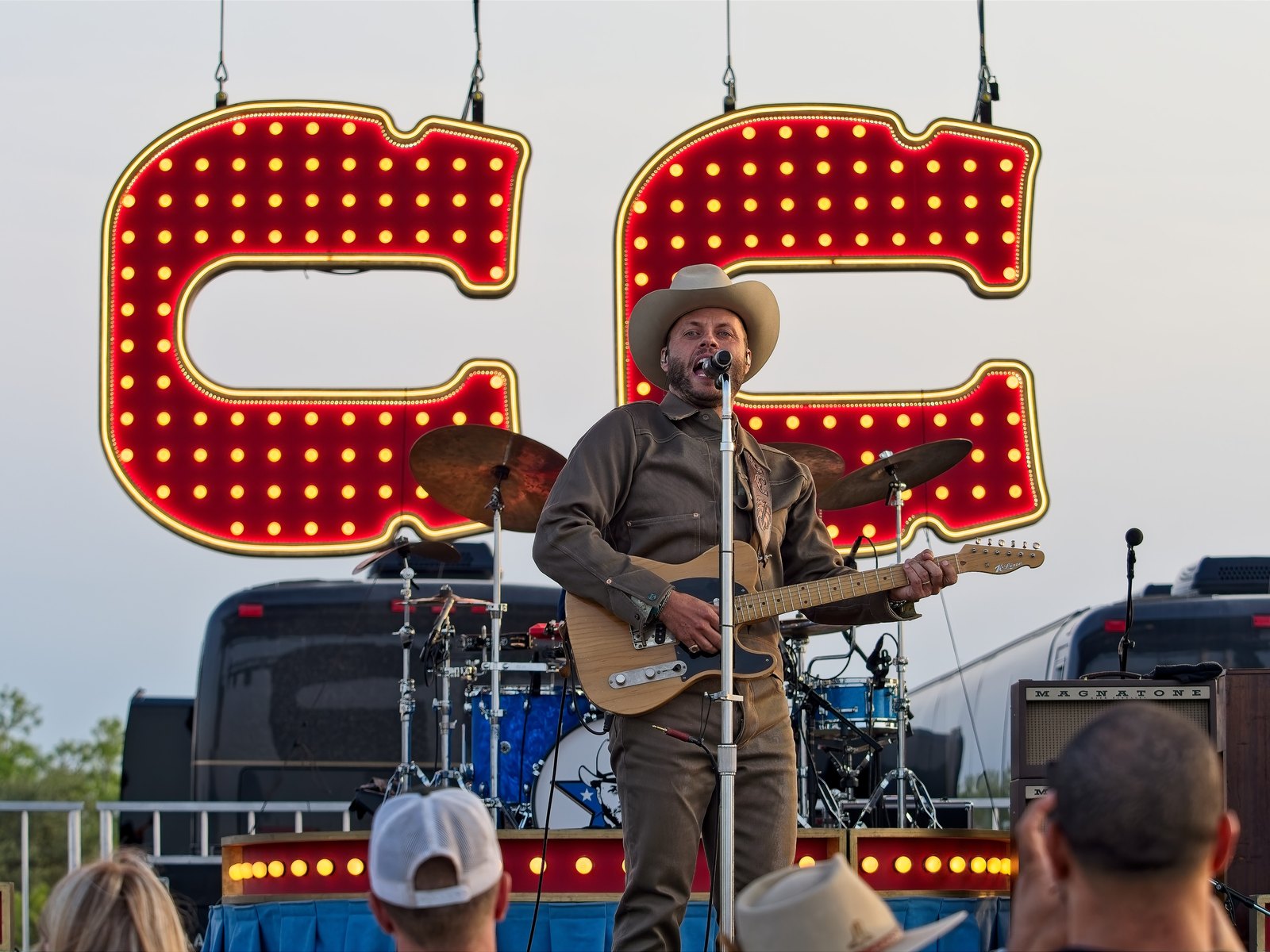 A country musician performing with a telecaster in front of large illuminated marquee letters